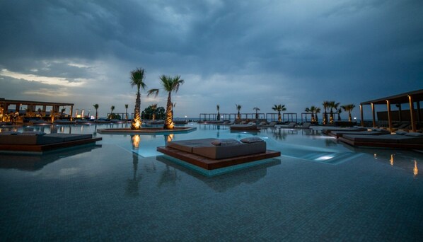 A pool area with lounge chairs and palm trees. - Senseana Seaside Resort And Aquadventure (Analipsis)