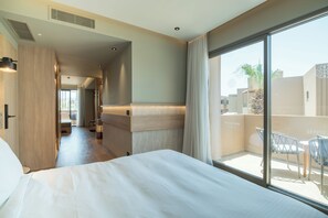 A hotel room with a large bed, a balcony with a view, and a hallway leading to other rooms. - Senseana Seaside Resort And Aquadventure (Analipsis)