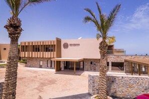 A modern building with a sign reading 'SENSEANA,' surrounded by palm trees and a clear sky. - Senseana Seaside Resort And Aquadventure (Analipsis)