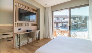 A hotel room with a bed, a desk with a chair, a TV, and a view of an outdoor swimming pool. - Senseana Seaside Resort And Aquadventure (Analipsis)