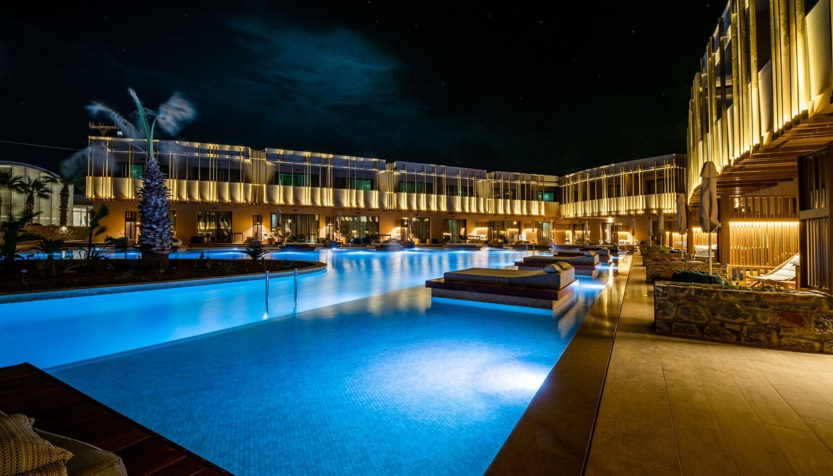 A nighttime swimming pool area with a modern building in the background.