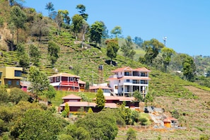 Un barrio residencial en una ladera, con casas, incluyendo un edificio de dos pisos con techo rojo y una construcción blanca con balcón.