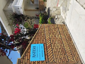 A reception area with a sign for Asteri Studios & Apartments, a brick-patterned roof, and surrounding greenery. - Asteri Studios (Zakynthos)