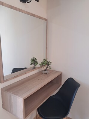 A room with a large mirror, a small potted plant, a wooden console table, and a black chair. - Asteri Studios (Zakynthos)