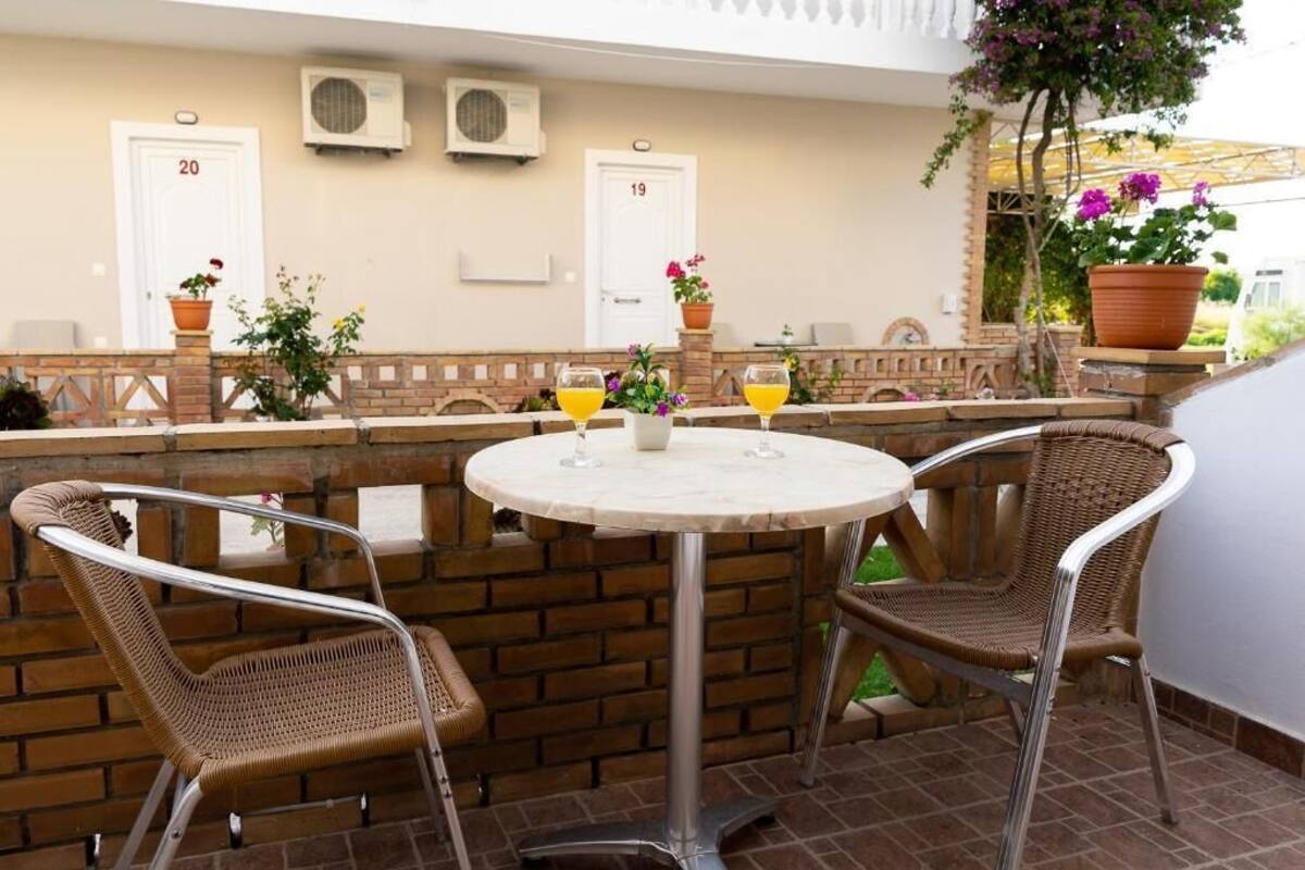 A patio with a round table, wicker chairs, and potted plants.
