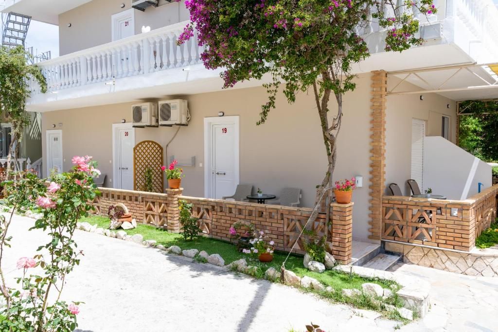 Un edificio a due piani con un balcone, posti a sedere all'aperto e un giardino.