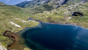 Een bergachtig landschap met een groot meer en een kronkelende weg.