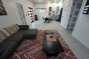 Un salon moderne comprenant un canapé d’angle, une table basse et un coin repas avec une table et des chaises.