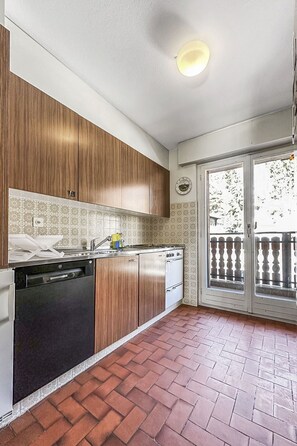 A kitchen with wooden cabinets, a dishwasher, and a stove. - Entre Pistes & Golf - Crans Montana by Interhome (Crans-Montana)