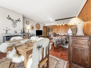 A spacious living area with a wooden dining table, a sofa set, and a fireplace. - Entre Pistes & Golf - Crans Montana by Interhome (Crans-Montana)