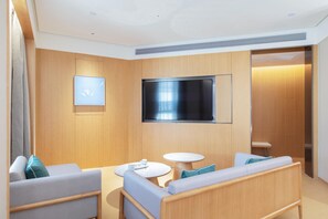 A modern hotel room with a flat-screen TV mounted on the wall, a sofa, a small round table, and a chair. - Ji Hotel Zhuzhou Tianyuan District Hunan Universit (Zhuzhou)