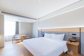 A hotel room with a large bed, two chairs, a small table, and a bedside table with a lamp and phone. - Ji Hotel Zhuzhou Tianyuan District Hunan Universit (Zhuzhou)