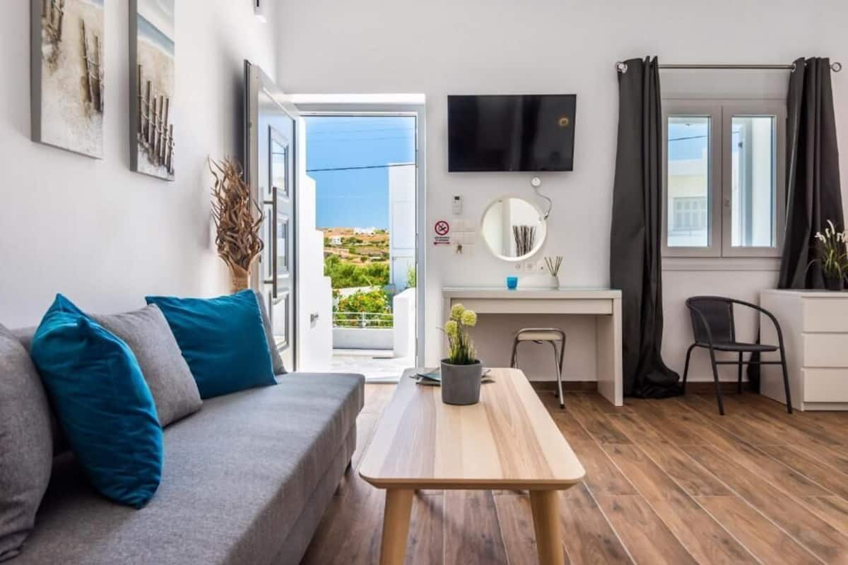 Un salon moderne avec un canapé, un bureau, un téléviseur et une vue sur l’extérieur.