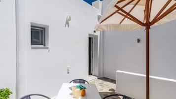 Um quarto branco com uma mesa, cadeiras, uma janela e uma porta.