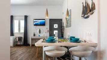 Uma cozinha moderna com área de refeições, piso de madeira e televisão presa na parede.