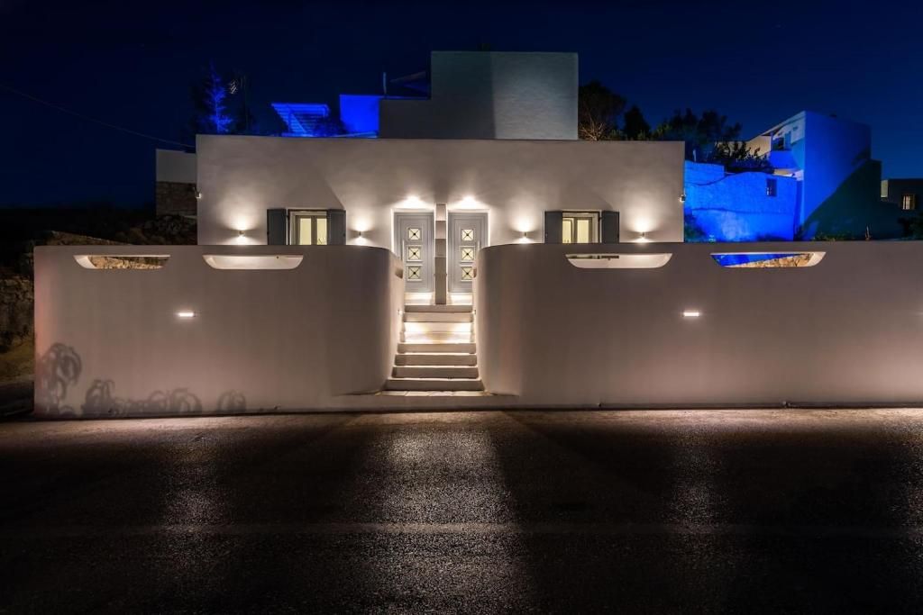 Um edifício moderno com uma escadaria que leva a uma porta, rodeado por paredes com iluminação integrada.