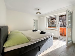 A bedroom with a bed, a window, and a balcony. - Eagle Apartement - Zermatt by Interhome (Zermatt)