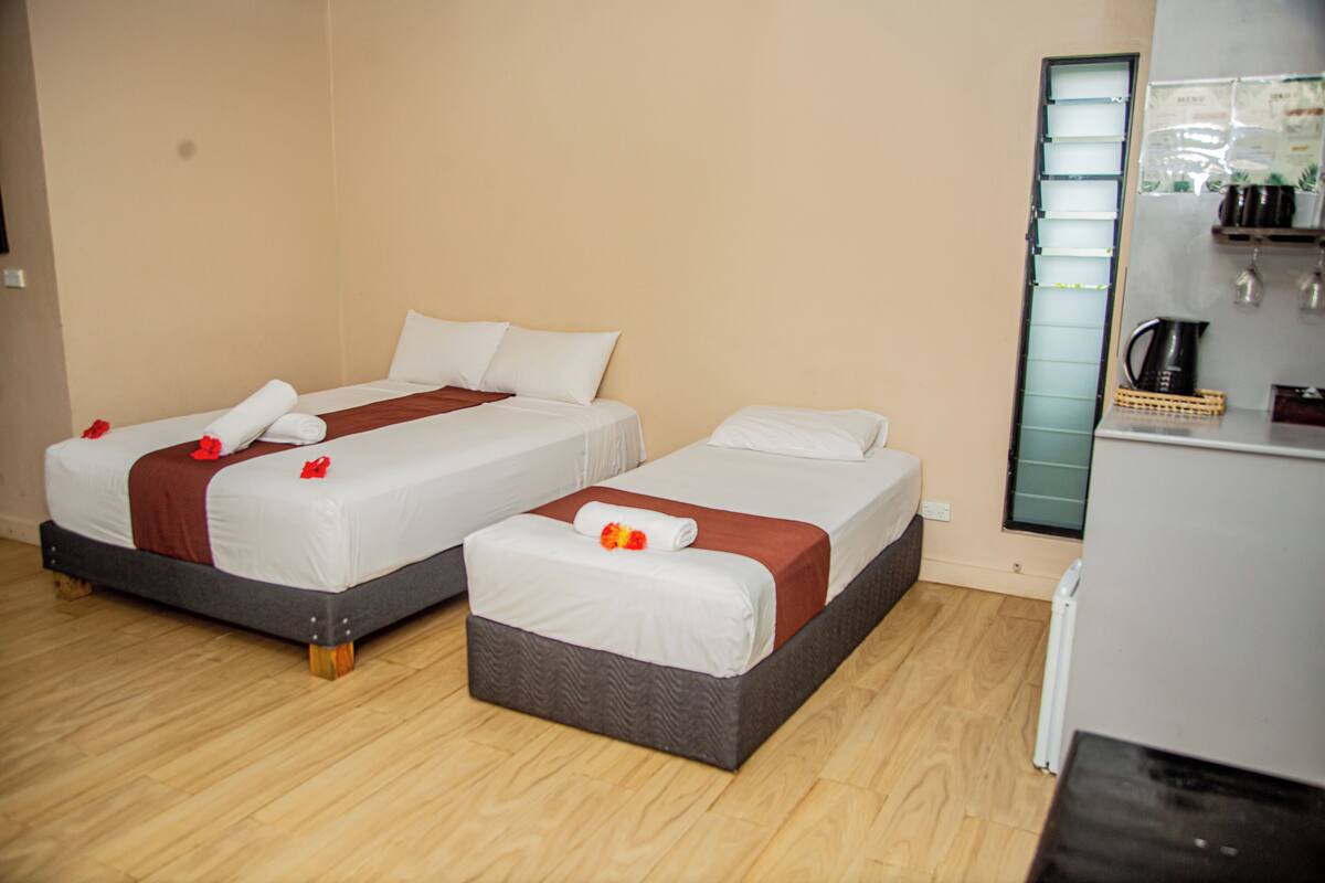 A hotel room with two beds, a kitchenette, and a mirror.