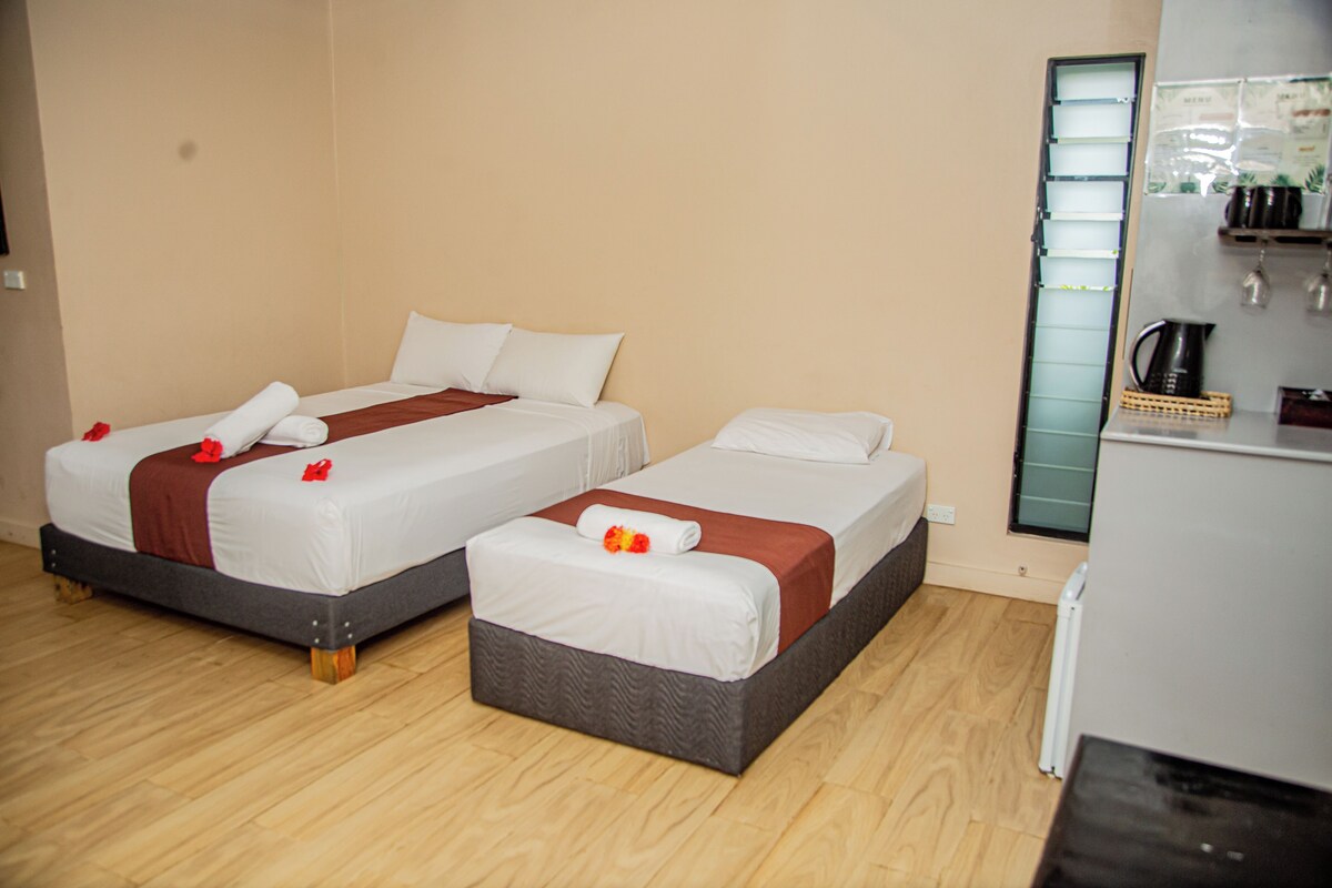 A hotel room with two beds, a kitchenette, and a mirror.