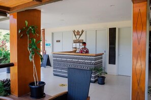 A reception desk with a sign, a receptionist, and a reception area with a patterned counter.