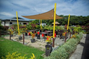 An outdoor seating area with tables and chairs, surrounded by potted plants and a large canopy. - Seatiki Fiji (Sigatoka)