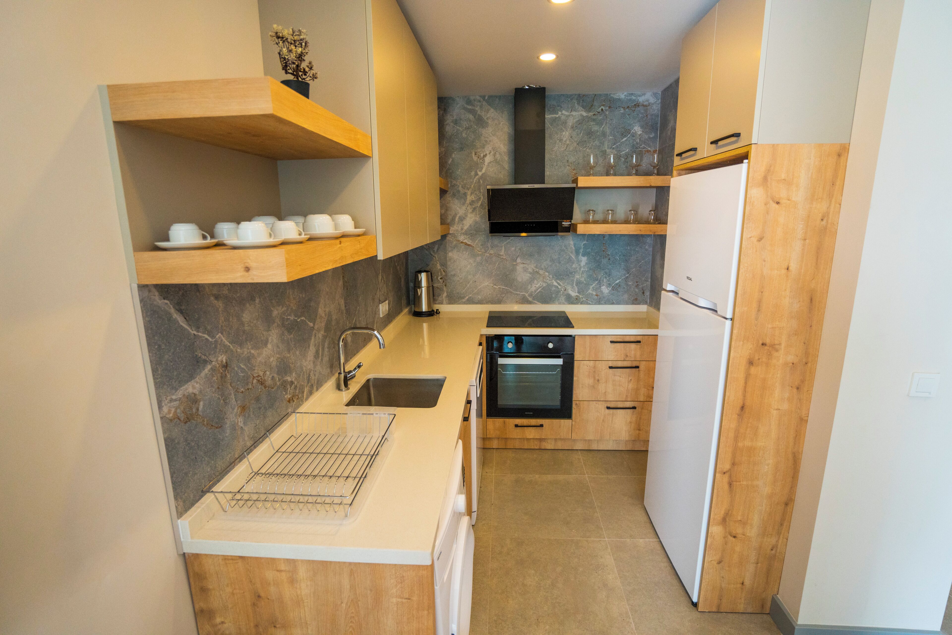 A compact kitchen with wooden cabinetry, a built-in oven, and a microwave.