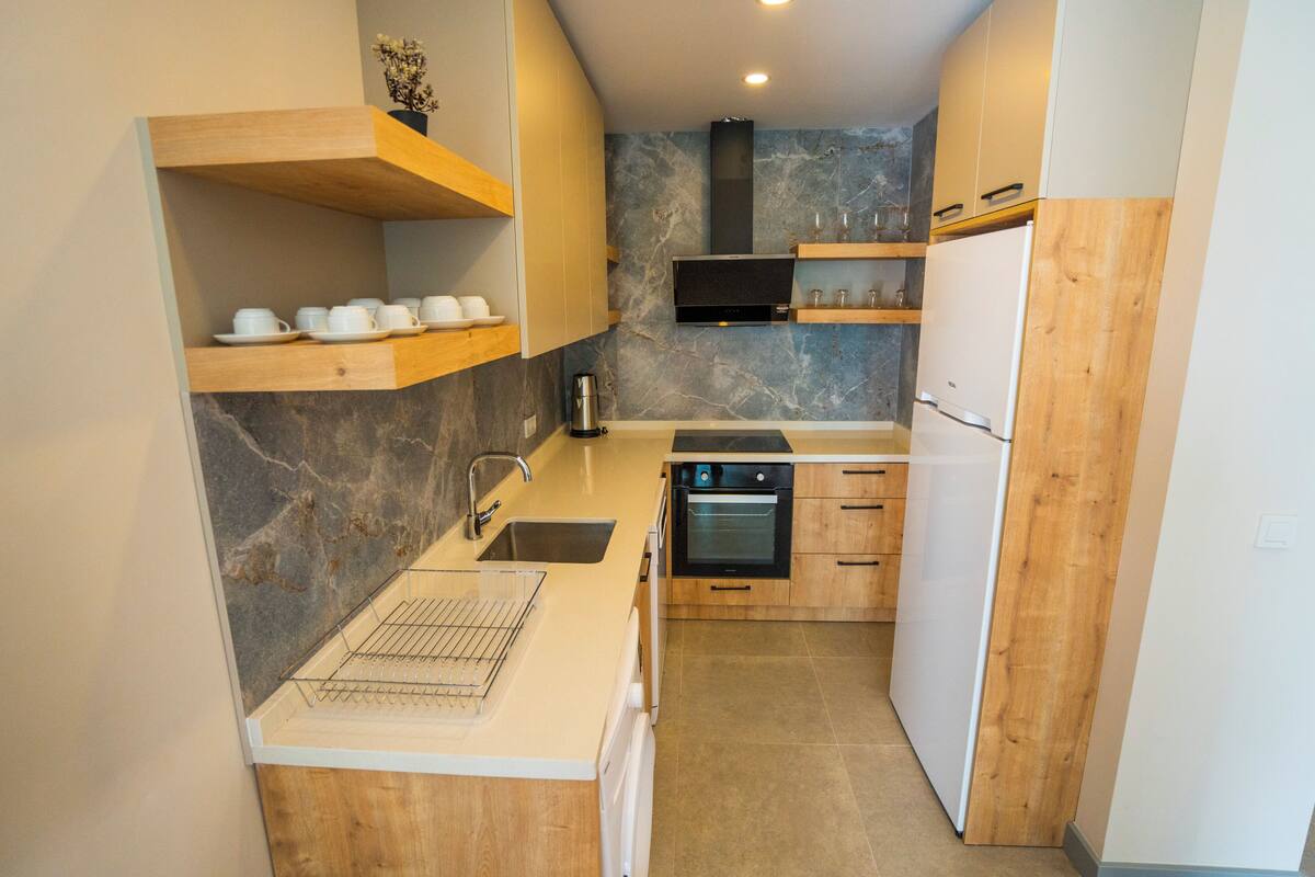 A compact kitchen with wooden cabinetry, a built-in oven, and a microwave.
