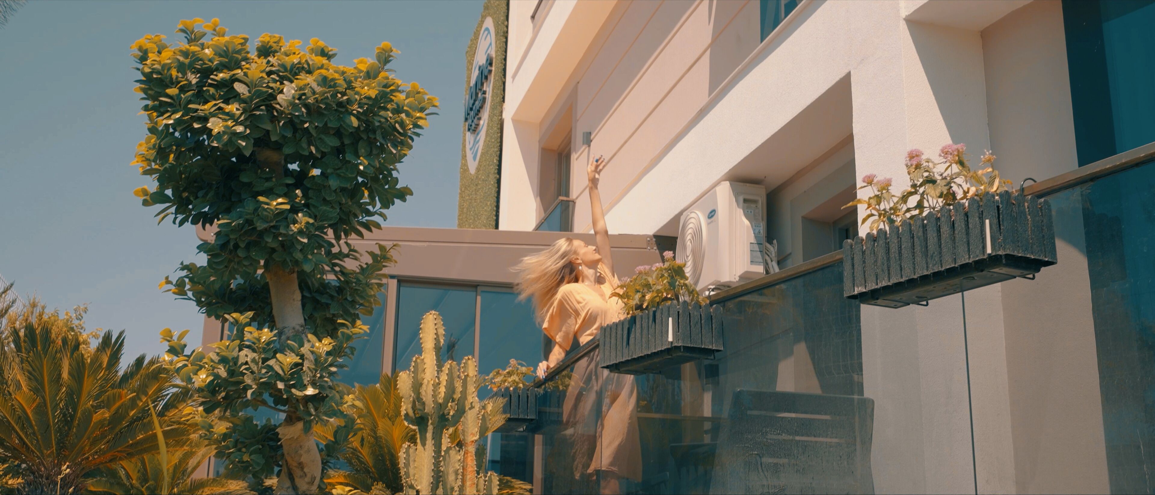 A building with a modern design, featuring a balcony with a railing and potted plants.