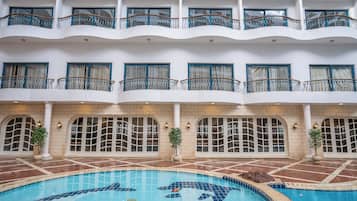 Un hotel a più piani con piscina, balconi e ampie finestre.