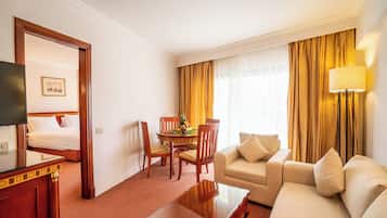 Una camera d'albergo con un letto, un divano, un tavolo da pranzo con sedie, una TV e una lampada.