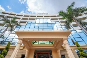 A modern hotel with a glass facade, palm trees, and a classical entrance. - Azal Pyramids Hotel (Kafr ad-Dawwar)