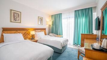 Una habitación de hotel con dos camas, un escritorio, una silla, cafetera y televisor.