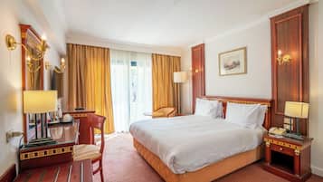 Une chambre d’hôtel avec un grand lit, un bureau avec une lampe, une chaise et une table de chevet avec un téléphone.