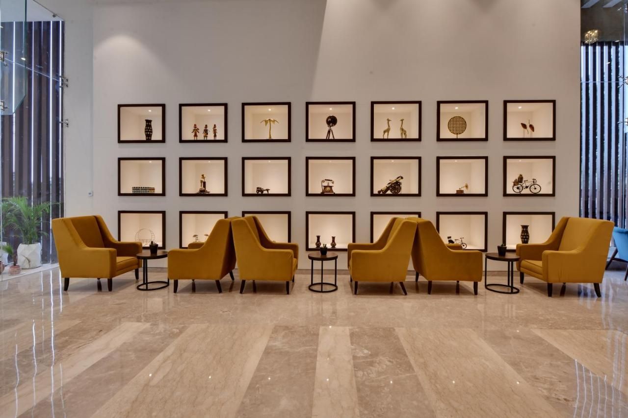 A lobby with a marble floor, yellow armchairs, and a wall of framed pictures.