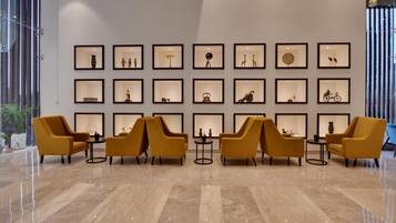 A lobby with a marble floor, yellow armchairs, and a wall of framed pictures.