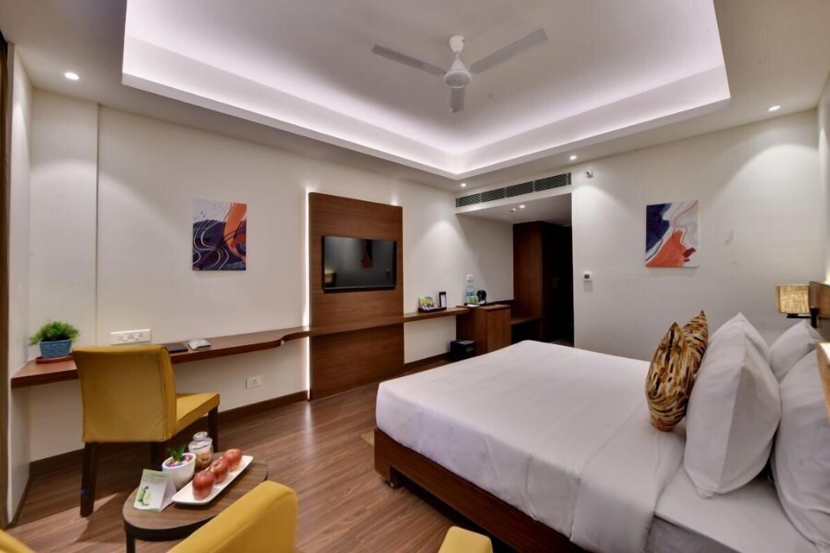 Una habitación de hotel moderna con cama, escritorio, silla, televisor y obras de arte en las paredes.