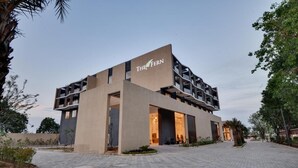 A modern building with a flat roof, a sign reading 'THE FERN,' and a paved entrance area.