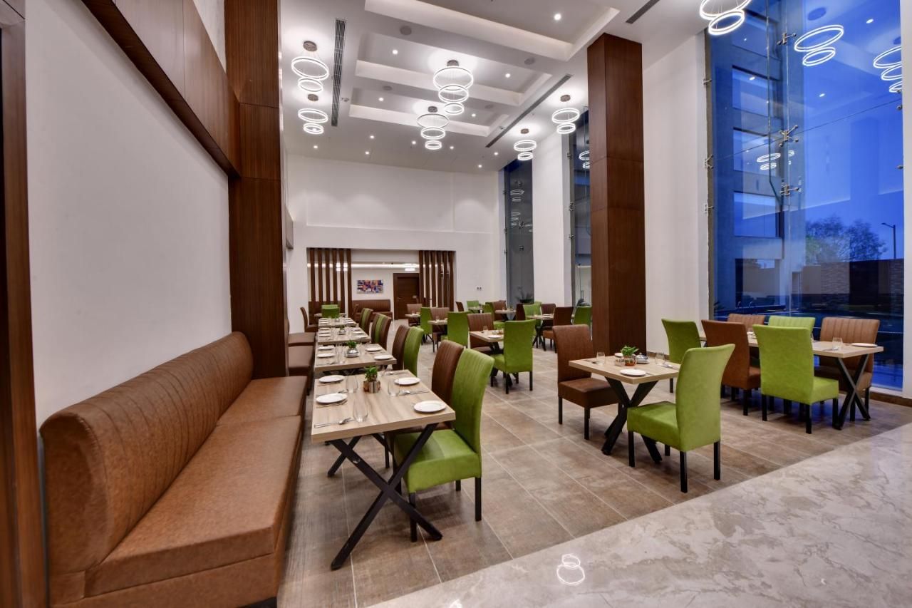 A spacious restaurant with high ceilings, modern lighting, and a mix of booth and table seating.