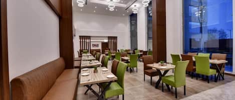 Un'ampia sala ristorante con soffitti alti, illuminazione moderna e un mix di posti a sedere con banconi e tavoli.