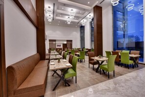 Un restaurante espacioso con techos altos, iluminación moderna y una combinación de asientos tipo cabina y mesas.