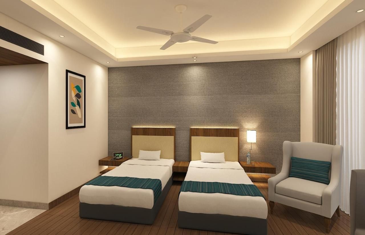 Une chambre d’hôtel avec deux lits, un ventilateur de plafond, une table de chevet avec une lampe et une chaise.