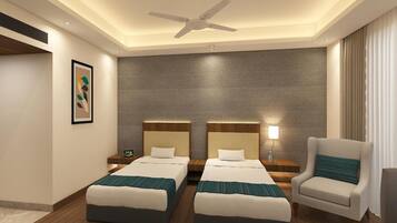 A hotel room with two beds, a ceiling fan, a nightstand with a lamp, and a chair.