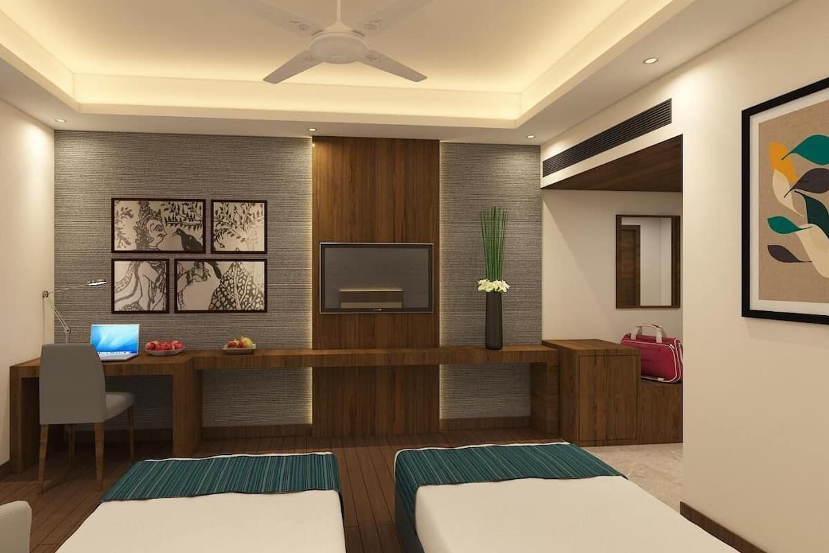 A modern hotel room with a wooden desk, a flat-screen TV, two beds, and artwork on the walls.