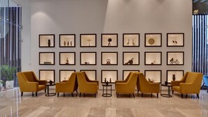 A lobby with a marble floor, yellow armchairs, and a wall of framed pictures.