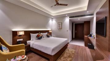 A modern hotel room with a large bed, a desk with a chair, a ceiling fan, and a TV mounted on the wall.