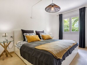 A bedroom with a large bed, a bedside table, a lamp, and a window with curtains. - La Casa Escaniana by Interhome (Santanyí)