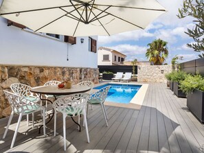 A poolside area with a table and chairs, a pool, and a stone wall. - La Casa Escaniana by Interhome (Santanyí)