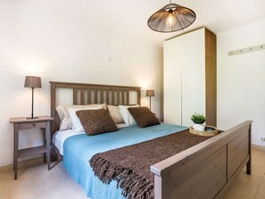 Une chambre à coucher comprenant un lit, des tables de chevet, un luminaire suspendu et une armoire.