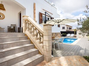 Un espace piscine doté d’une terrasse en pierre, d’un escalier avec des balustrades et de mobilier d’extérieur.