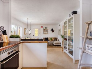 A modern kitchen with a central island, a dining area with a sofa, and a white cabinet with glass doors. - La Casa Escaniana by Interhome (Santanyí)